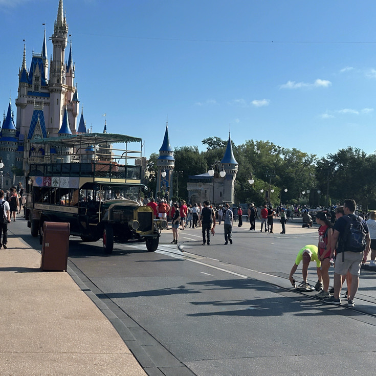 Main Street vehicle departing from Cinderella Castle at Magic Kingdom, rolling past cheerful guests as it makes its way down the vibrant, bustling main street.