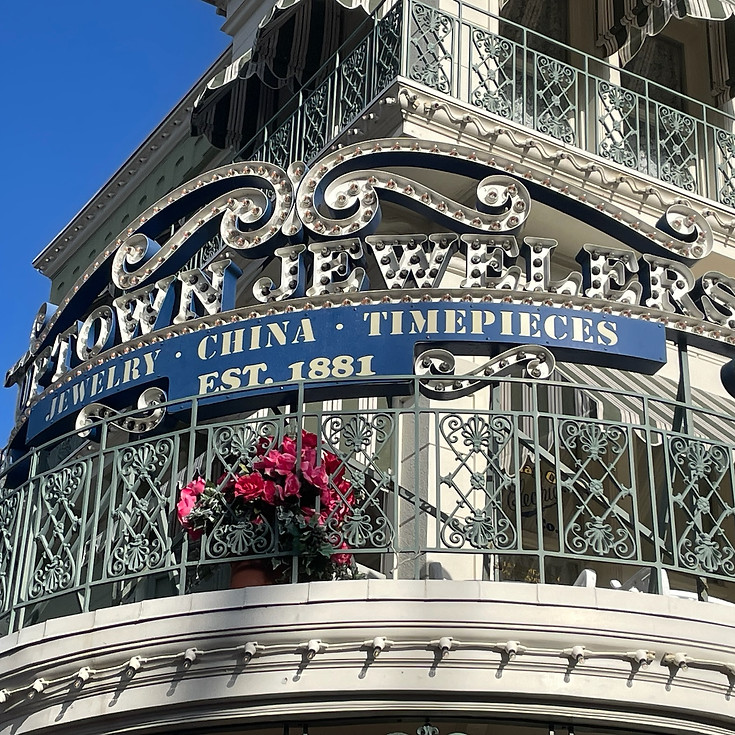 Uptown Jewelers on Main Street U.S.A., an elegant shop with ornate columns, gold accents, and upscale Disney-themed jewelry and fashion.
