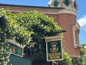 Wrought Iron trellis covered in white flowers and green leaves, with a "Rose & Crown" sign