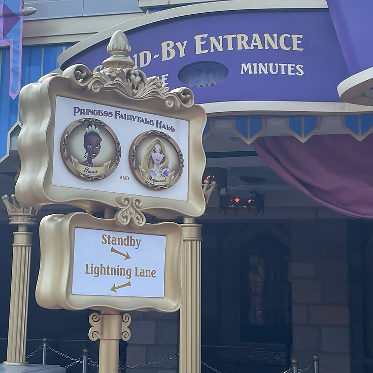 Sign for Princess Tiana and Rapunzel meet and greet inside Princess Fairytale Hall at Magic Kingdom, with elegant scrollwork and royal flourishes near the castle-style entrance.