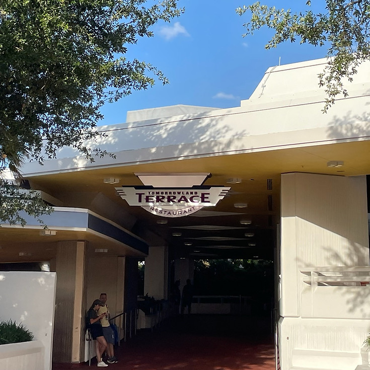 Tomorrowland Terrace at Magic Kingdom, with its modern, angular pavilion, open-air seating and red and white sign.