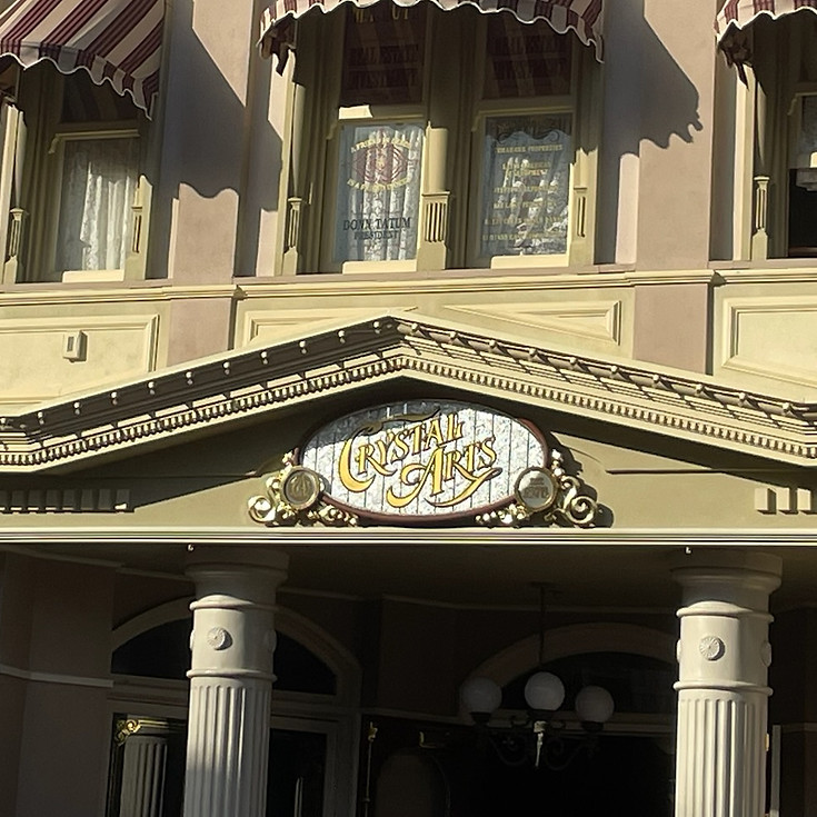 Crystal Arts on Main Street U.S.A., a sparkling shop with large glass windows, ornate white trim, with a white and gold sign and dazzling handcrafted glassware.