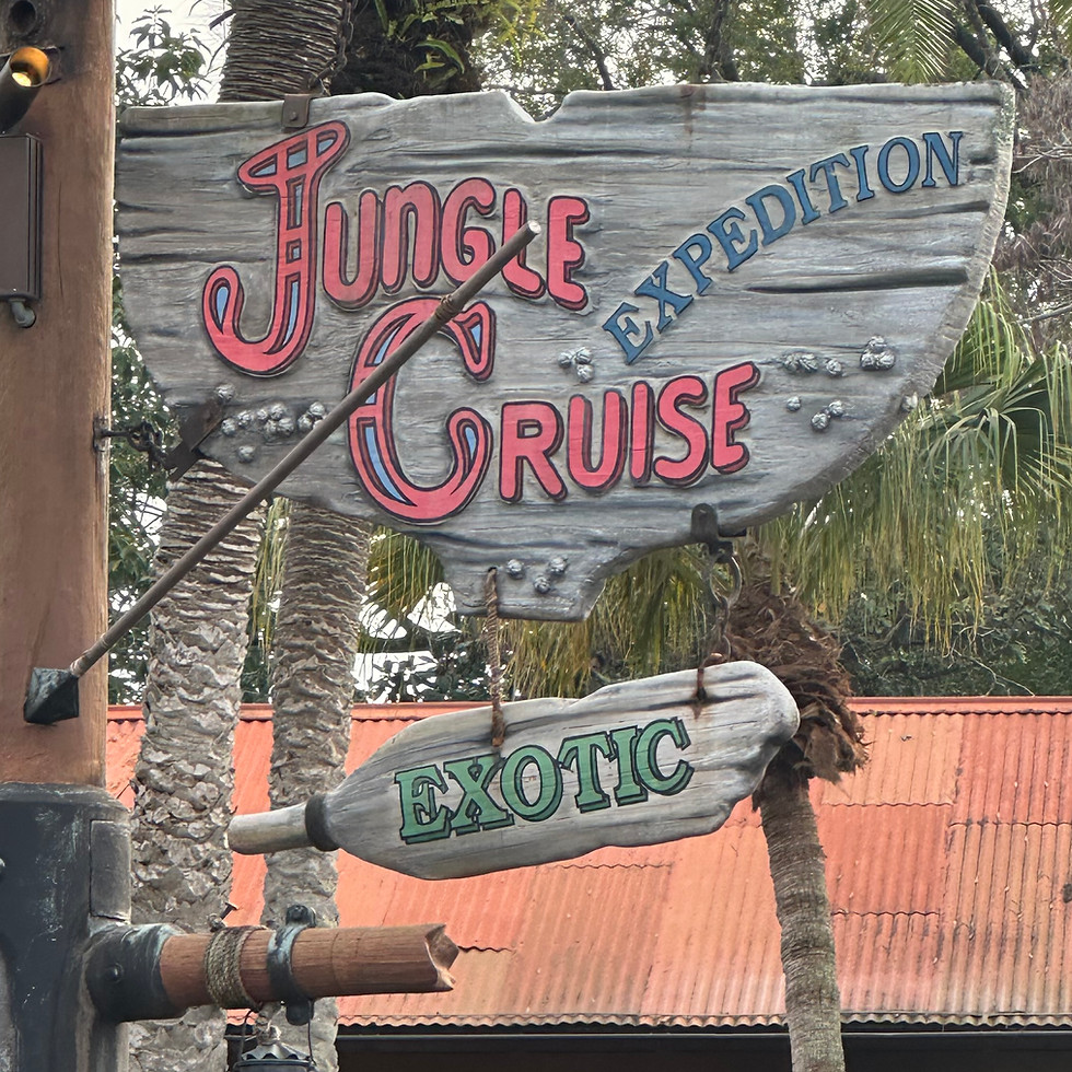 Jungle Cruise sign at Magic Kingdom, featuring rustic wooden lettering with lanterns and rope details, set above the boathouse-style entrance surrounded by tropical foliage and adventure-themed decor.