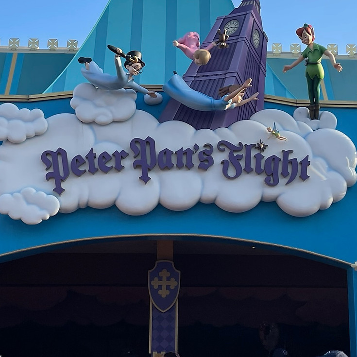 Peter Pan’s Flight entrance sign at Magic Kingdom, featuring a whimsical design with golden lettering, a flying ship motif, and illustrations of Peter Pan soaring above the ride’s enchanted entryway.