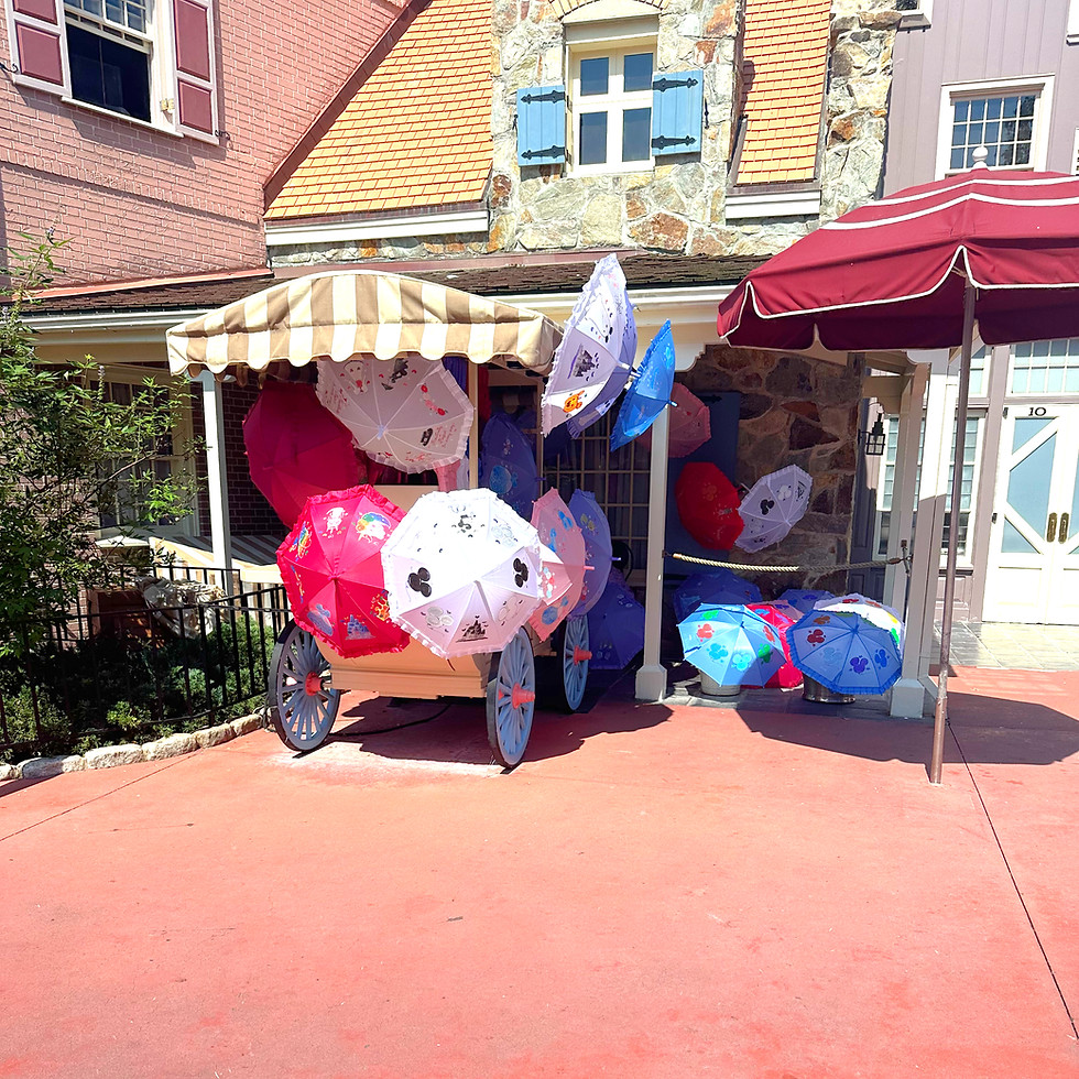 The Liberty Square Parasol Cart, a quaint colonial-style stand offering lacy parasols in pastel colors, nestled near cobblestone pathways.