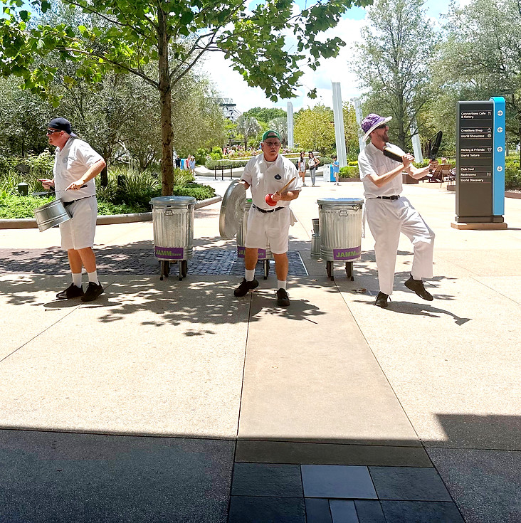 JAMMitors performing on trash cans with trees in the background