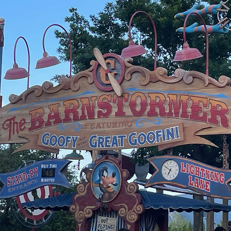 The Barnstormer sign at Magic Kingdom, featuring Goofy as the Great Goofini, with colorful circus-style lettering and playful aviation-themed details above the entrance.