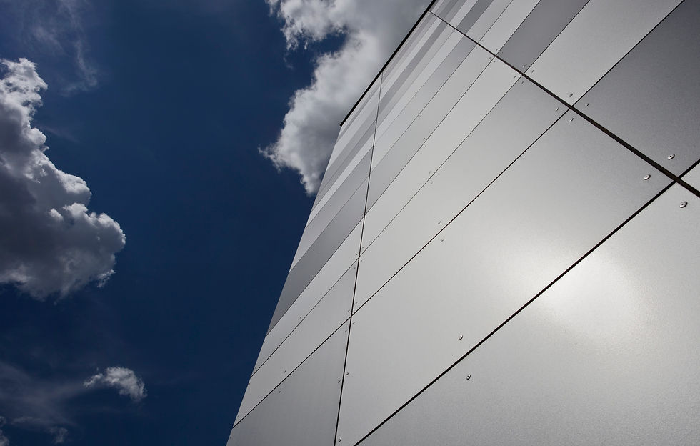 Metallic building panels reflect sunlight against a cloudy
