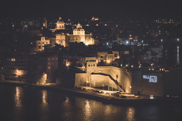 Beleuchtete Stadt bei Nacht mit Wasserspiegelung.