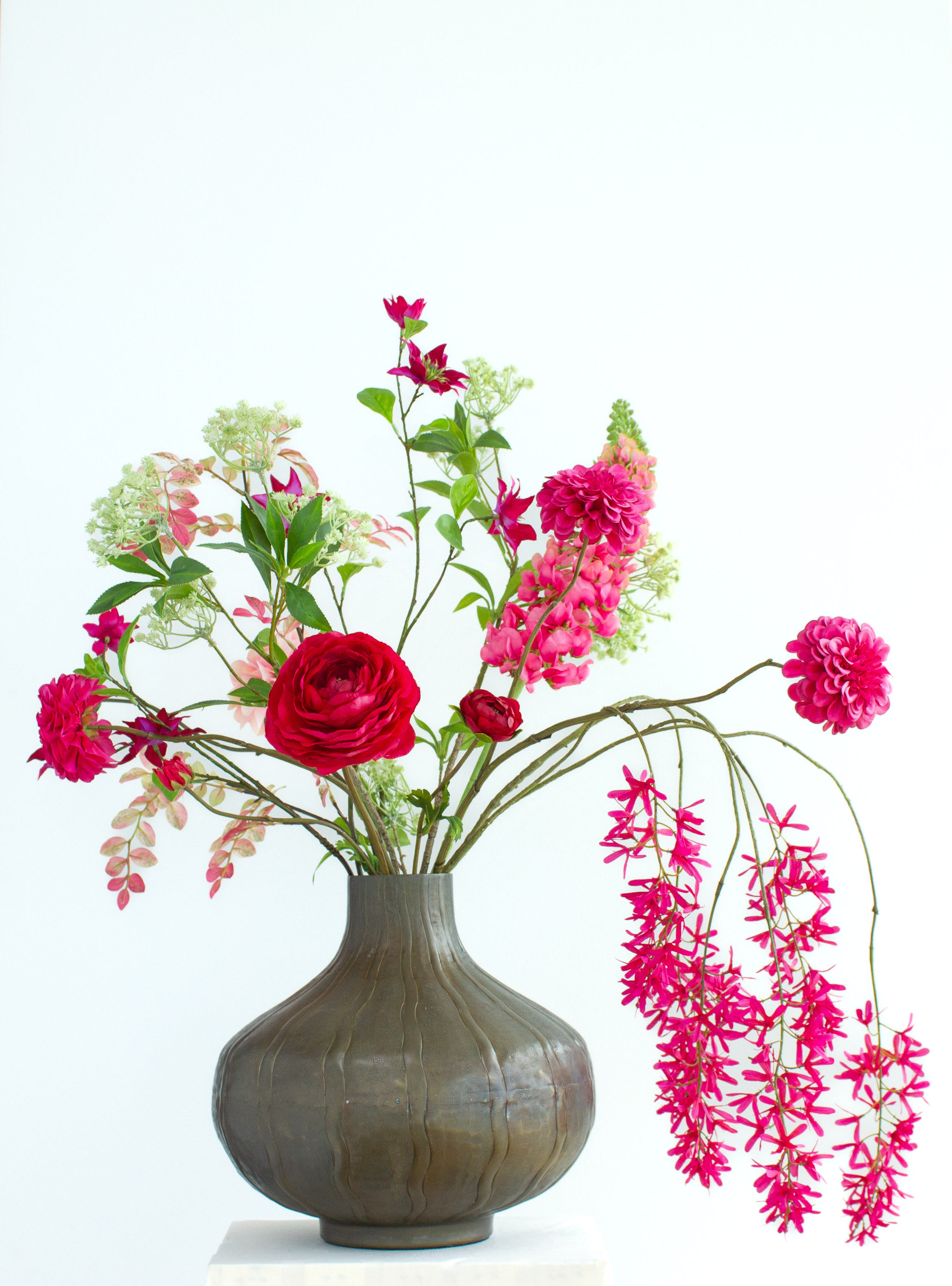 Large pink silk flower arrangement in white ceramic hourglass vase