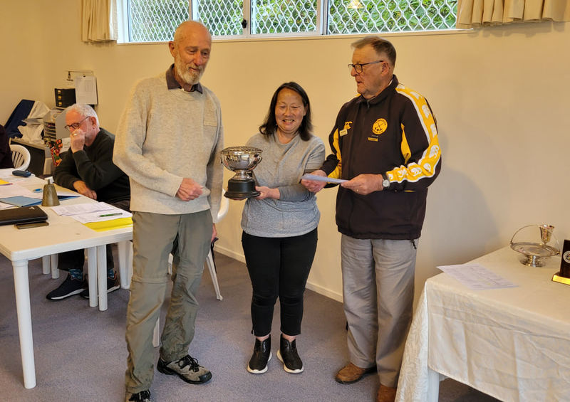 Woman receives a trophy from two men at an awards ceremony