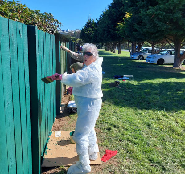 Volunteer painting a green fence
