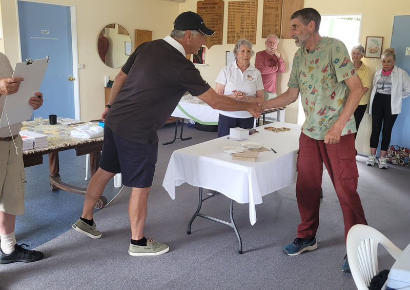 Two men shaking hands at an indoor gathering
