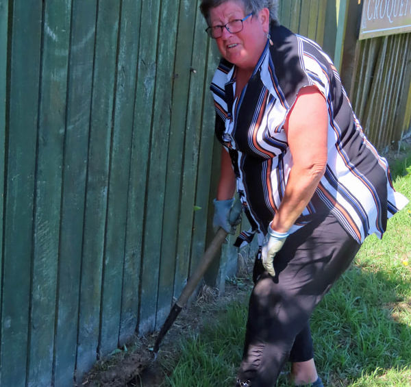 Woman digging dirt next to a green fence