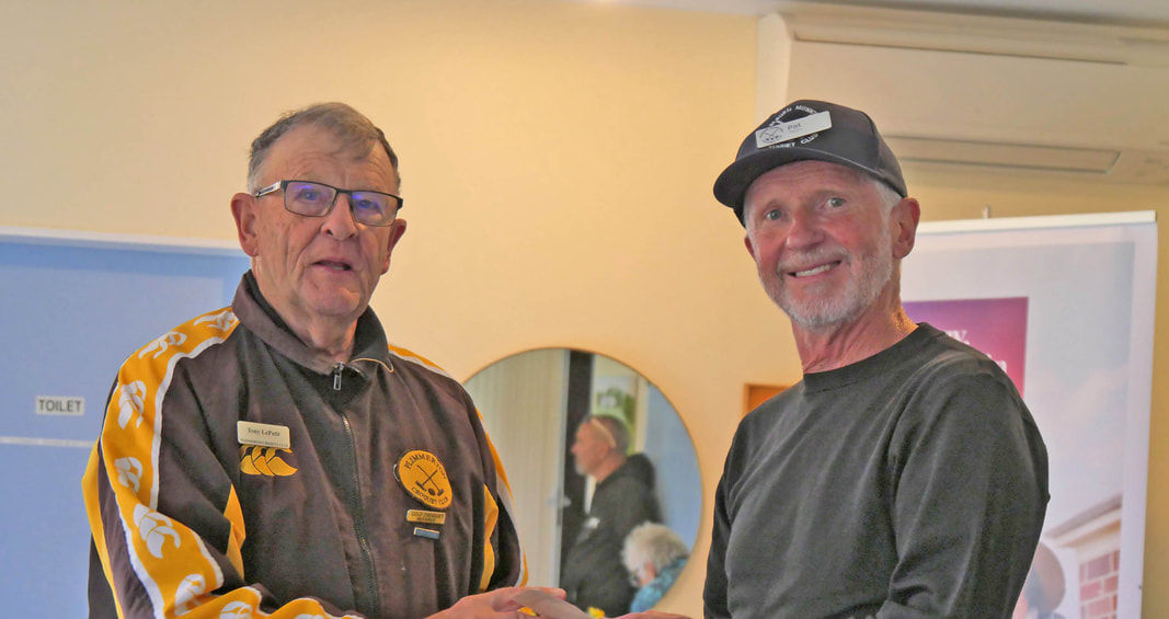 Man in jacket presenting award to man in black shirt
