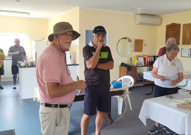 Man in hat speaking to two people indoors