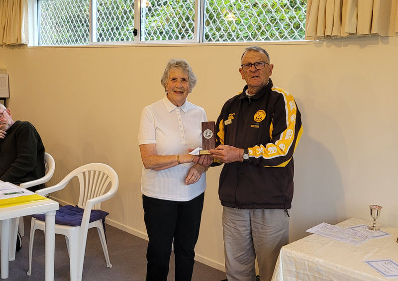 Woman presenting award to man in striped jacket