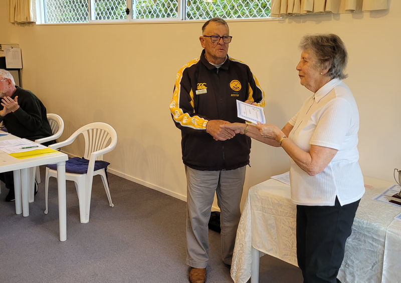 Man in yellow jacket hands document to woman