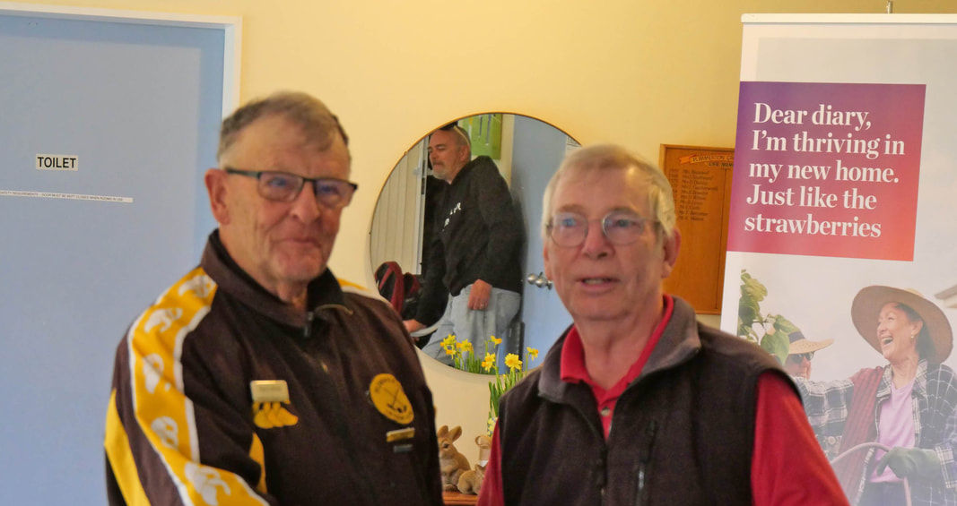 Two men shaking hands, one in a brown and yellow jacket