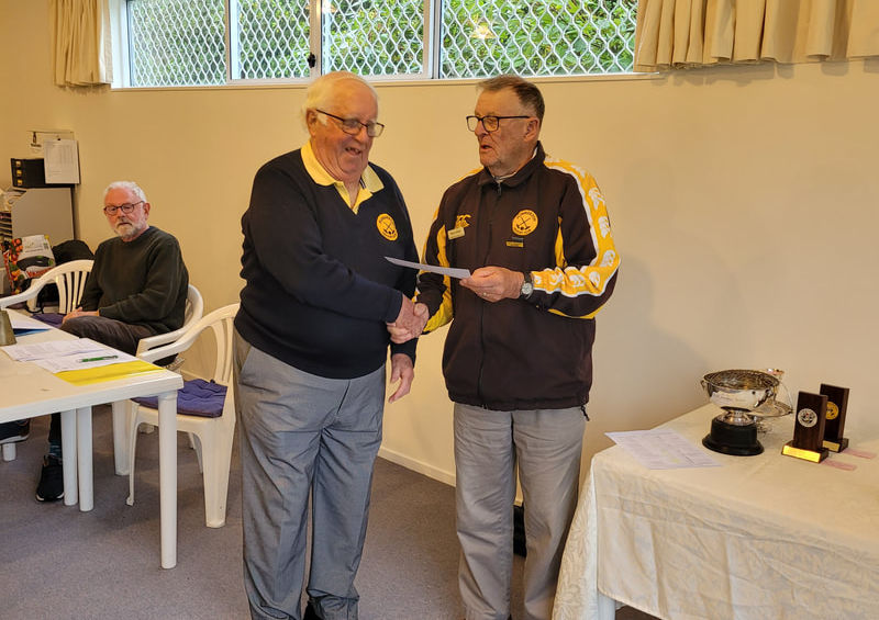 Two men shaking hands and exchanging an award at an event