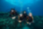 Group of scuba divers underwater, exploring the ocean with safety equipment.