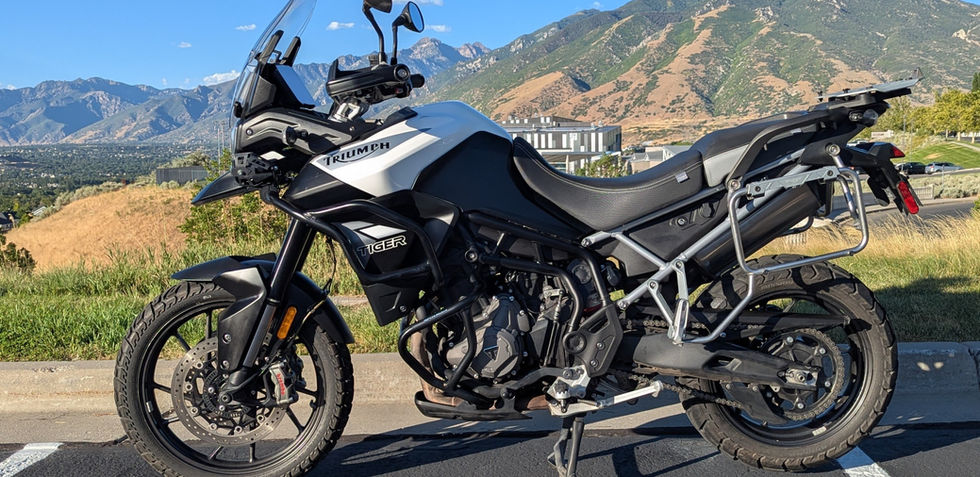 A white motorcycle parked in front of a mountain, seen from the left side