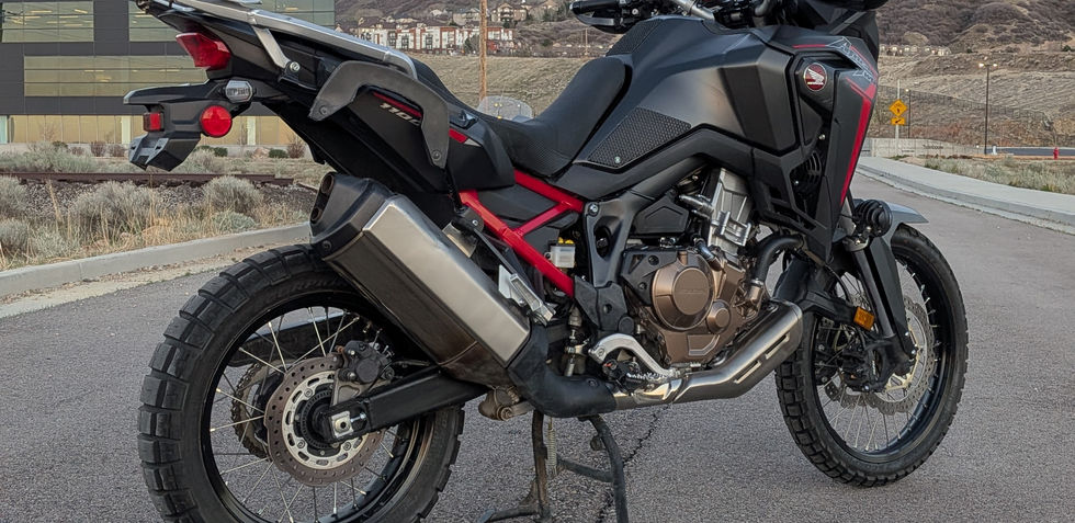 Side view of a motorcycle in front of a mountain and building