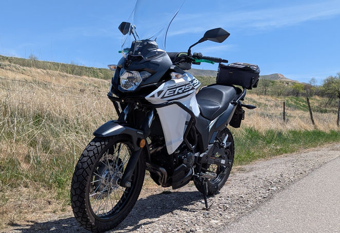 A small white motorcycle parked in front of a field of grass