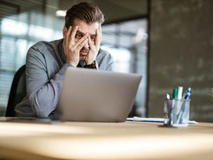 Man with head in hands behind a laptop