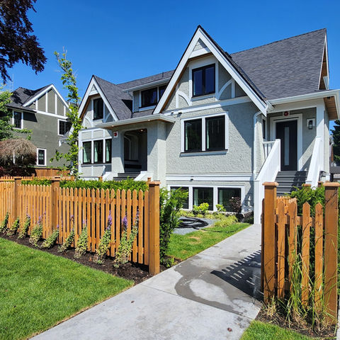 Courtyard view of a Shaughnessy character retention project showing the relocated 1924 Tudor Revival house and a modern rear infill duplex with pitched metal roofs.