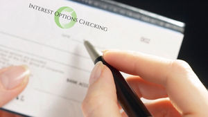 A person fills out an interest-earning checking account check, highlighting financial management with added benefits.