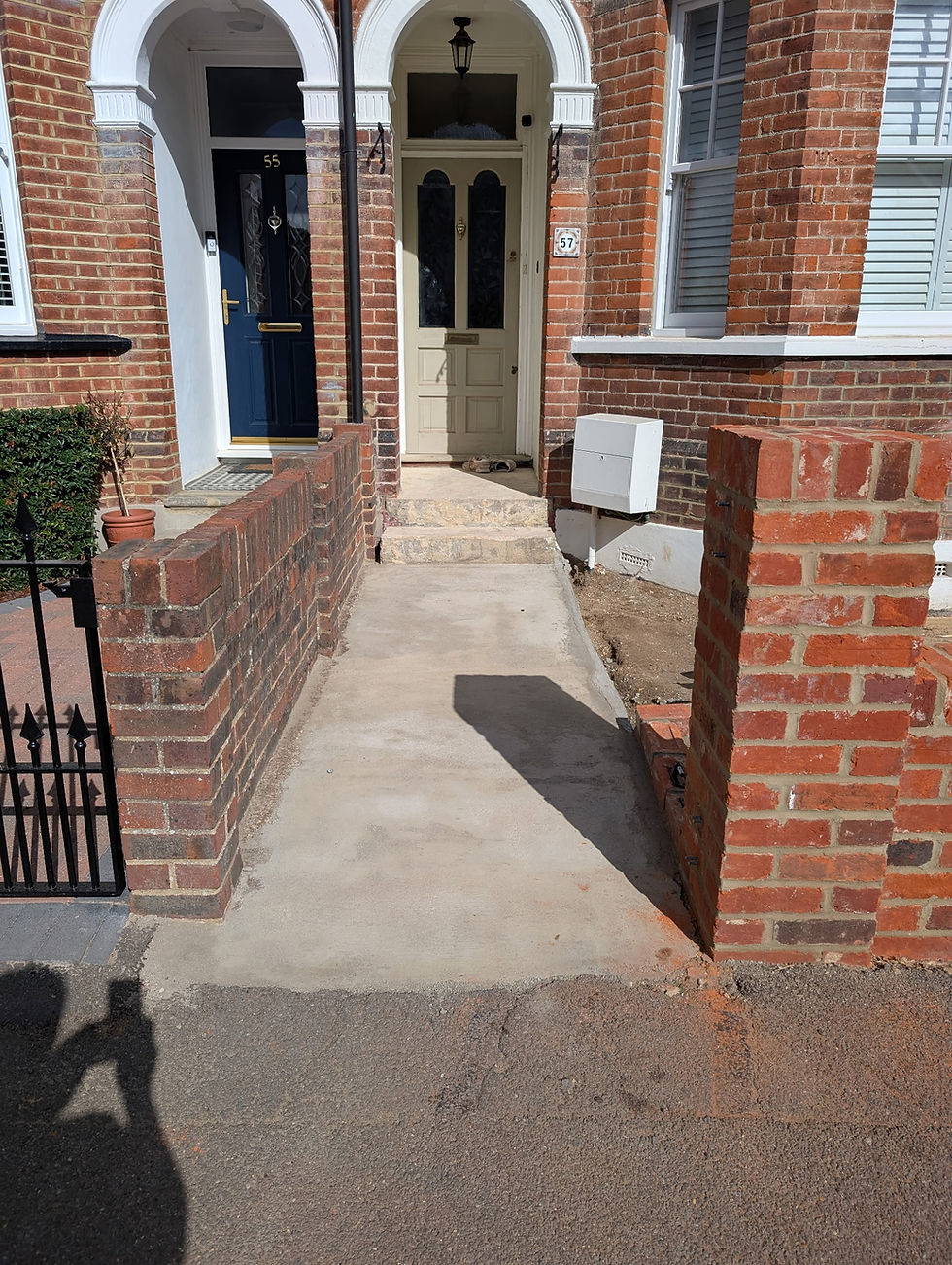 Tall brick garden wall leading to a front door path.
