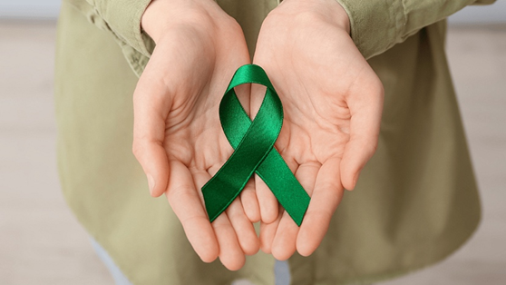 Green mental health awareness ribbon in open hands