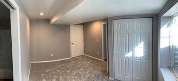 gray bedroom with carpet and 3 doors into bathroom, hall and closet, large window and recessed lighting