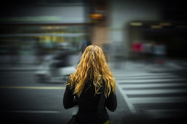 Frau mit langen blonden Haaren steht an einer belebten Straßenkreuzung