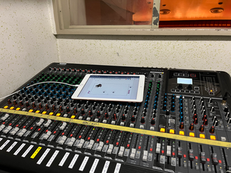 ミキサーとタブレット。操作画面が表示されています。音響設備の調整です。