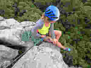 Climber attached to anchors using the climbers rope at the top of a climb
