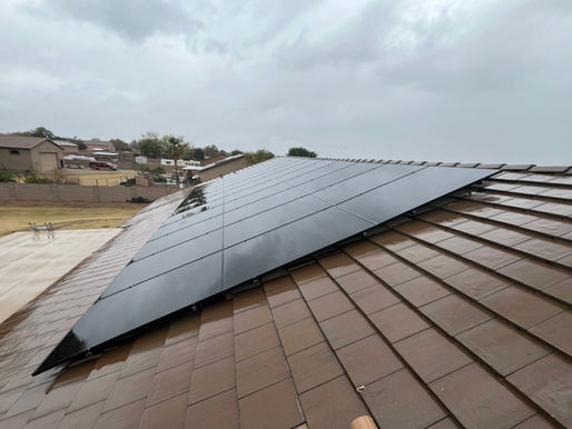 Solar panels on a rooftop stand resilient against the backdrop of an approaching summer storm, highlighting the importance of sustainable energy solutions during potential power outages.