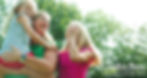 Carolyn Bosn laughs with two young girls outdoors beneath the trees.