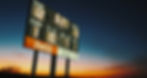 A football scoreboard is silhouetted against a Nebraska sunset.