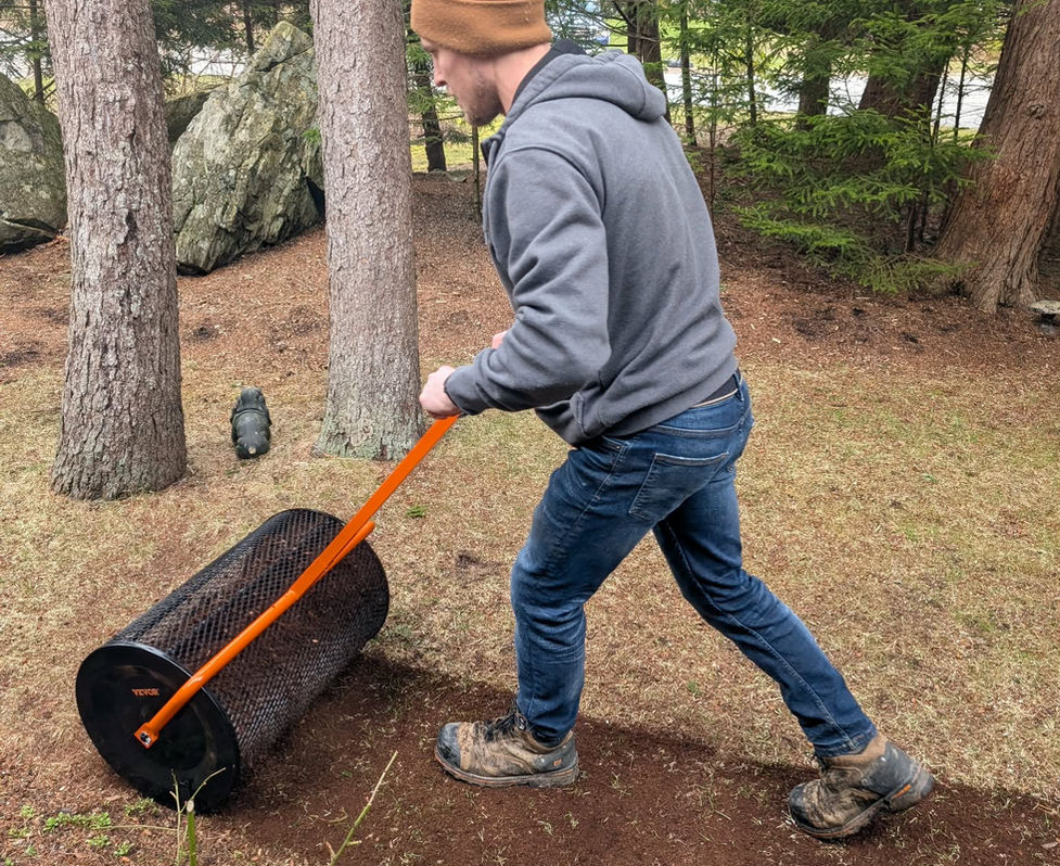 Top dressing application by NovaGrass Turf Care using a filled lawn roller to evenly spread soil during residential lawn renovation.