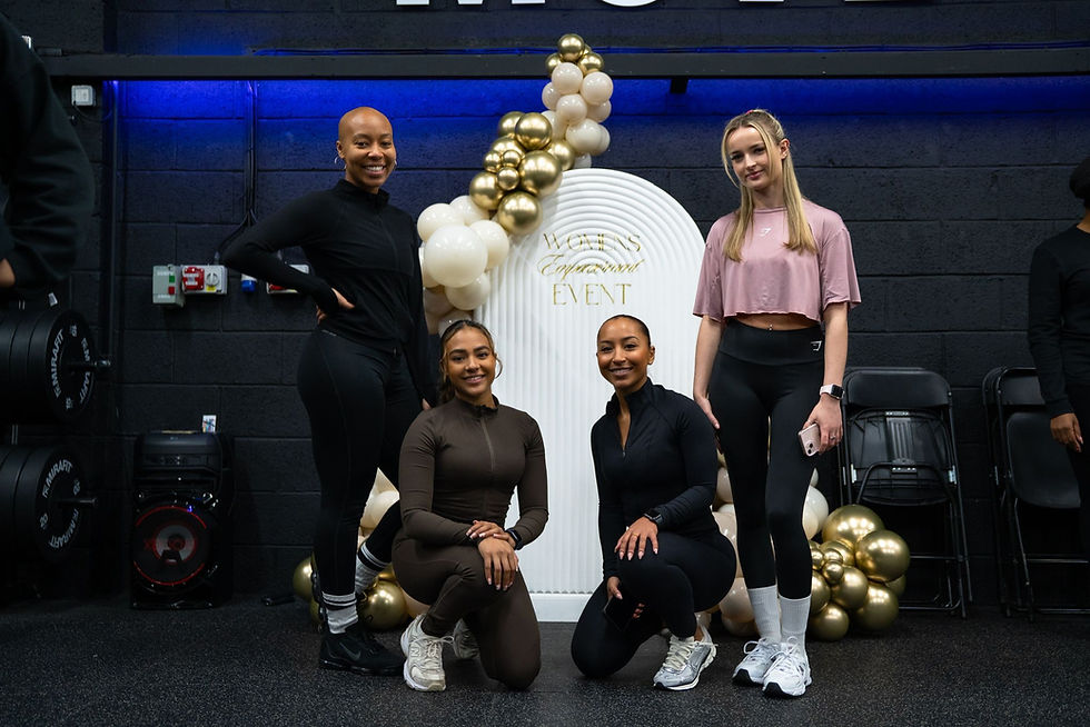 TCFit female members smiling in front of decorative back drop at the TCFit womens empowerment event