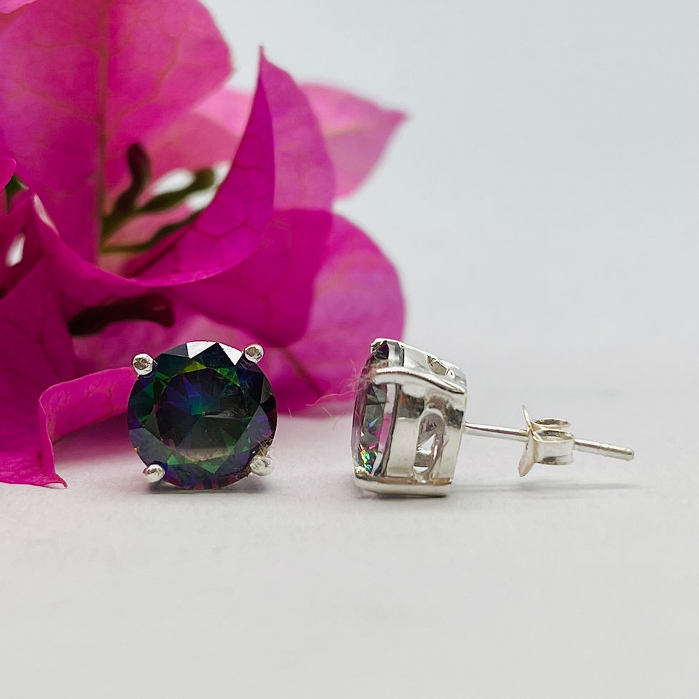 Mystic topaz stud earrings with round iridescent gemstones in silver settings, displayed beside a pink flower.