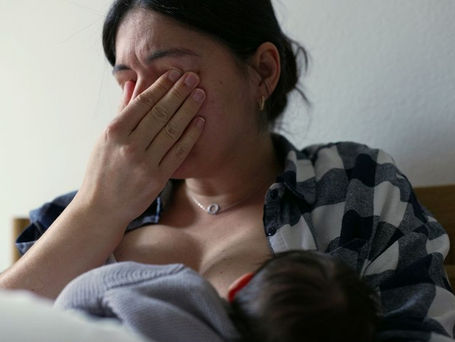 Mãe amamentando bebê com apoio de consultora de amamentação