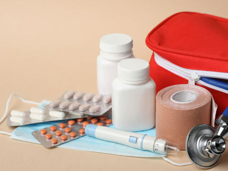 Farmacinha de viagem com medicamentos, curativos e itens de primeiros socorros organizados sobre uma mala aberta