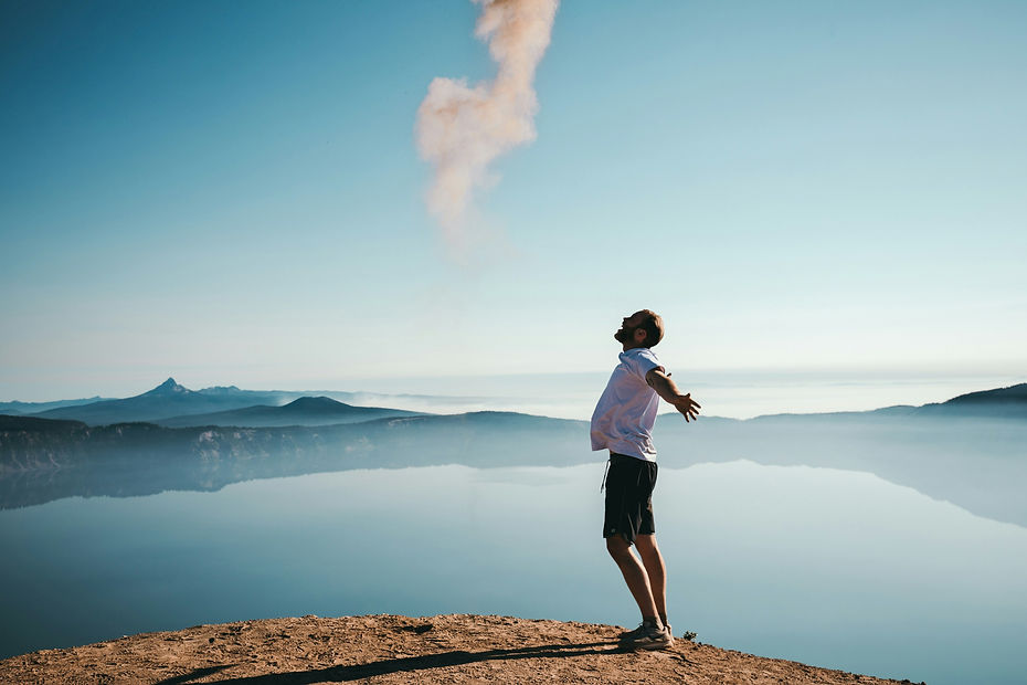 Man standing on mountain with arms in the air feeling happy