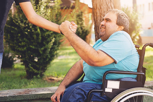 Man in wheelchair at the park shaking hand.
