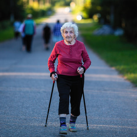 Older woman walking with two walking canes outside in the evening.