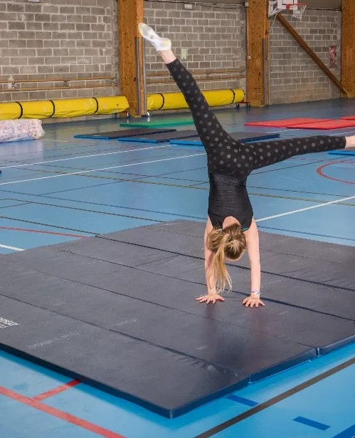 Fille faisant des exercices de gymnastique sur un tapis rose dans une boutique de gymnastique.