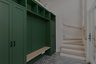 A stylish interior showing a home extension by Yorcon in Melbourne. On the left is a dark green built-in mudroom or entryway cabinet with a bench. On the right, a modern staircase with light wood steps and a simple handrail leads upstairs. The text overlay reads, "Home Extensions in Melbourne."